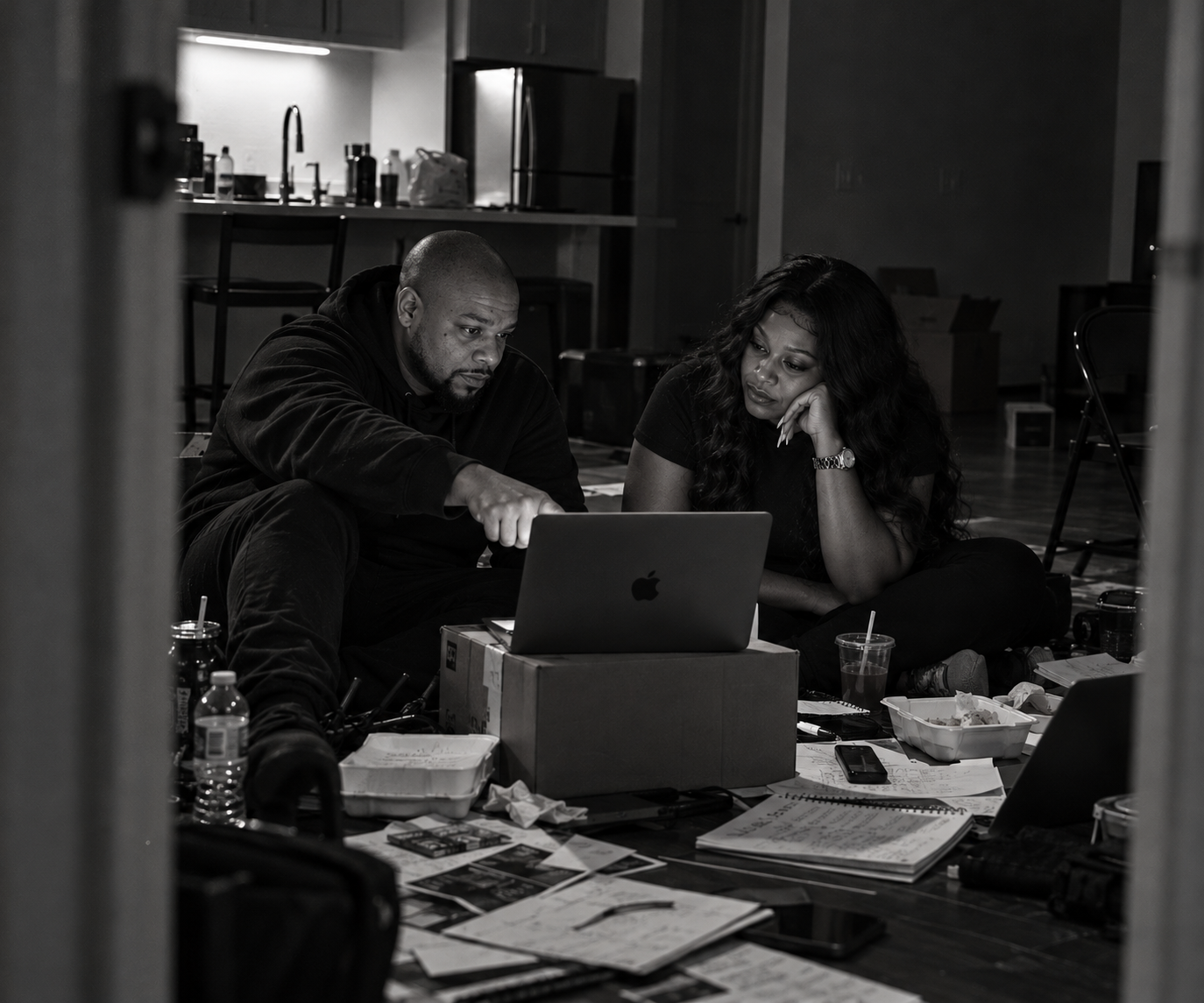 Eric Hunter and ReRe Hunter reviewing work together around a laptop in a black-and-white scene